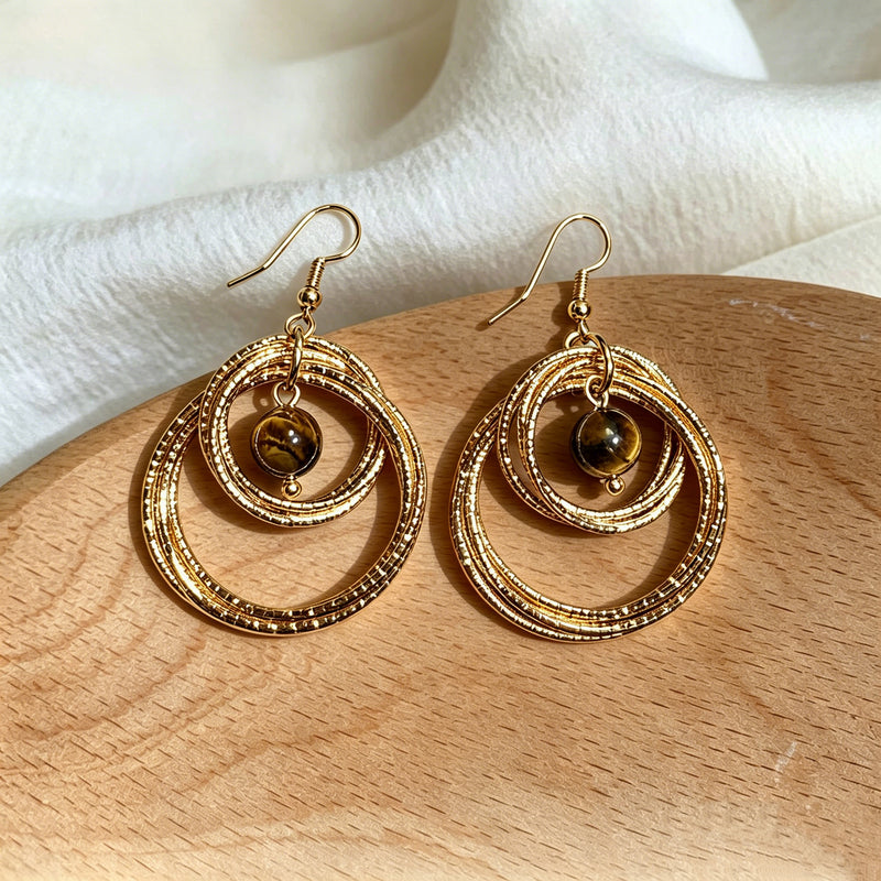 Gold hoop earrings with a central bead on a wooden surface